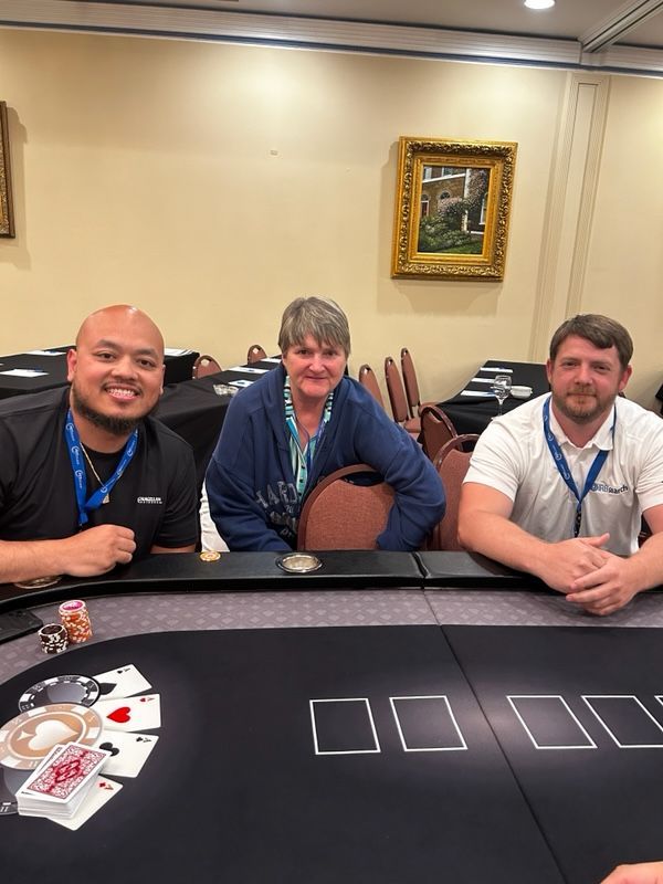 A group of people are sitting at a poker table.
