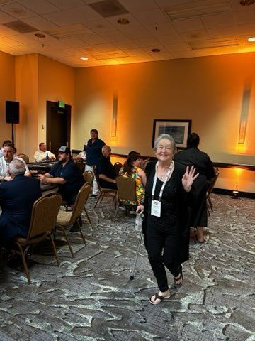A woman is walking through a room with people sitting at tables.