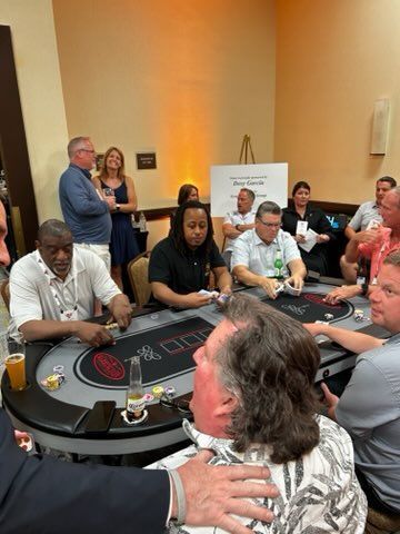 A group of people are sitting at poker tables in a room.