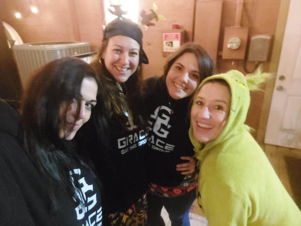 Four women are posing for a picture and one has a green hoodie on