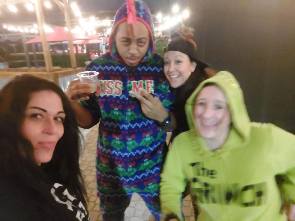 A group of people posing for a picture with one wearing a green hoodie that says the grinch