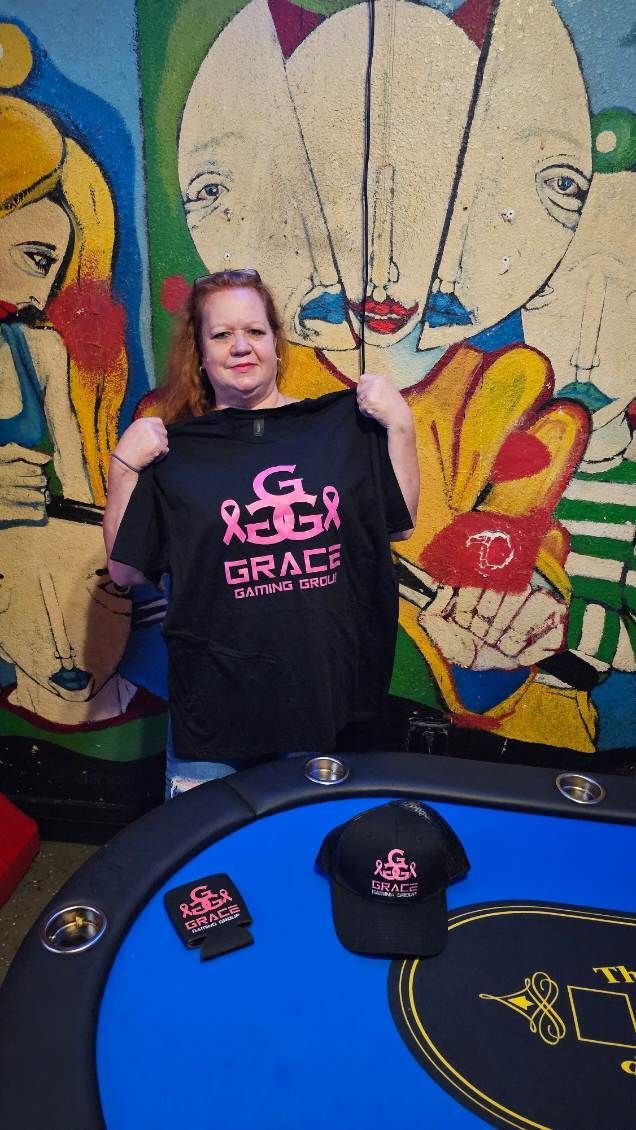 A woman is holding a t-shirt in front of a painting.