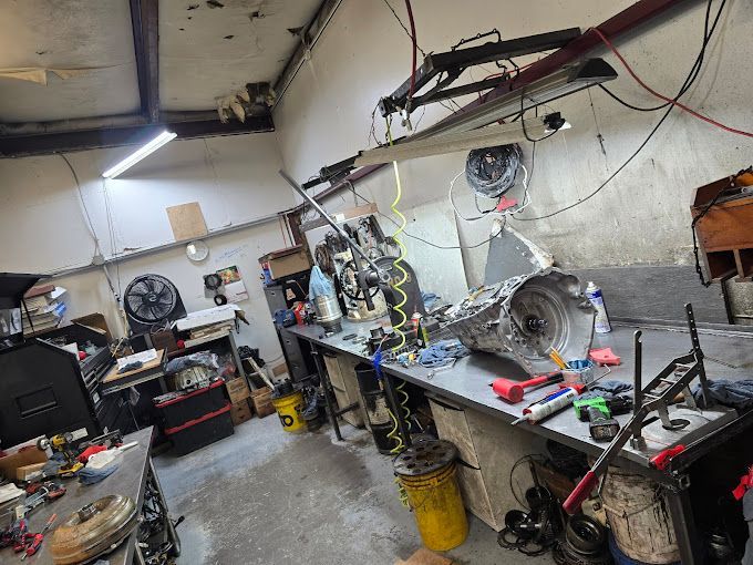 A garage filled with lots of tools and a table with a gearbox on it.