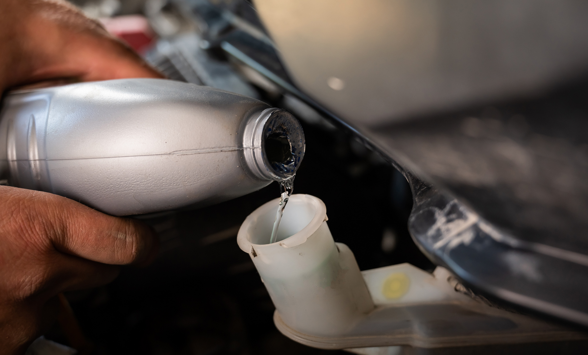 A person is pouring oil into a plastic container.