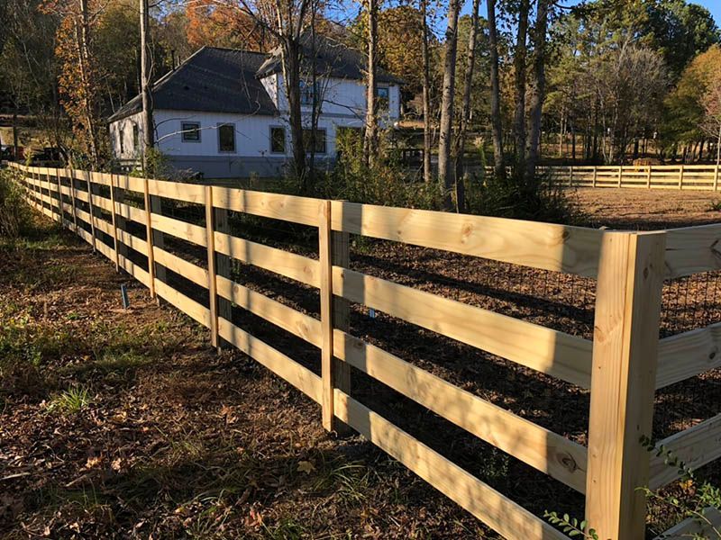 A wooden fence is surrounding a house in the woods.