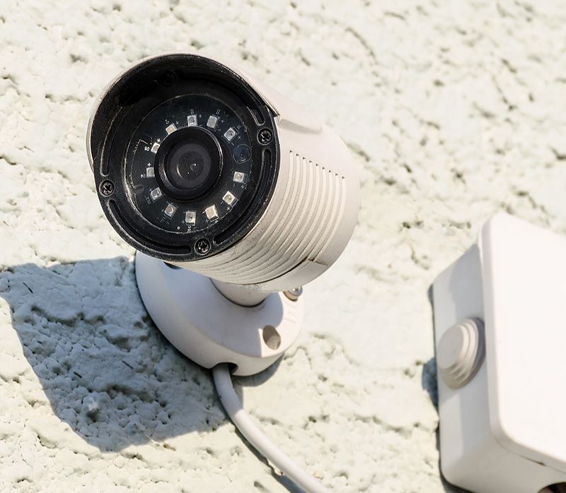 A security camera is attached to a white wall