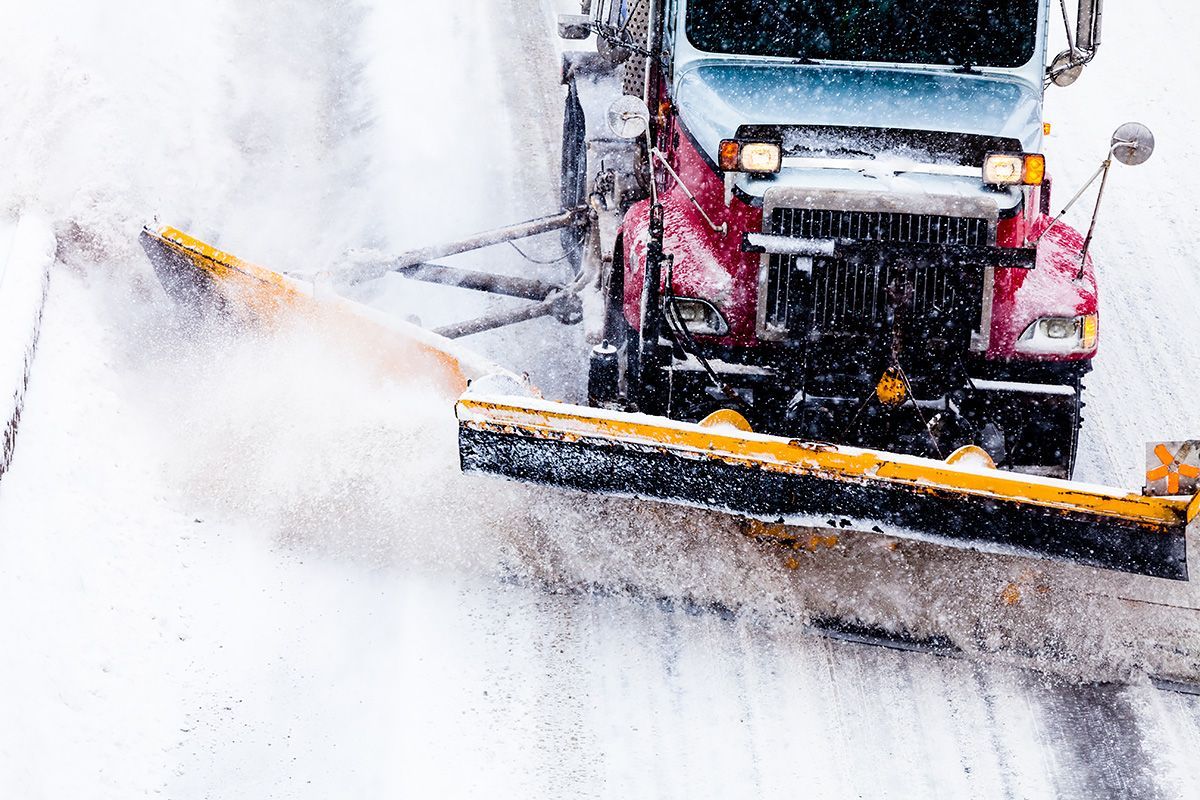 A snow plow is clearing snow from the road.