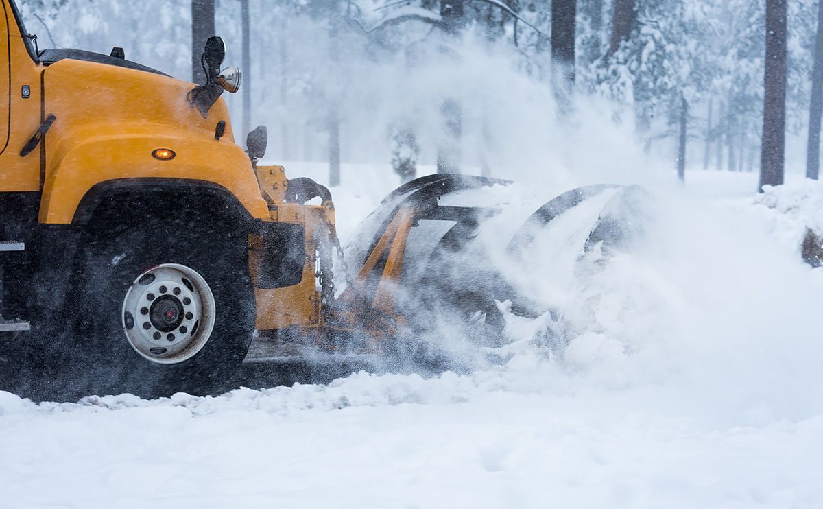 A yellow snow plow is clearing snow from a road.