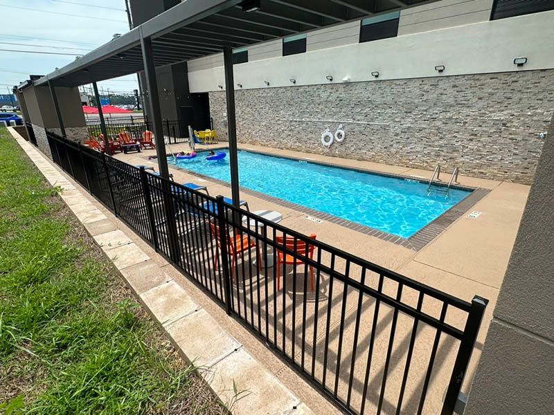 A large swimming pool is surrounded by a black fence.