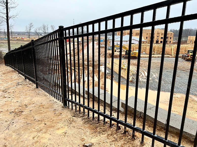 A black metal fence is surrounding a construction site.