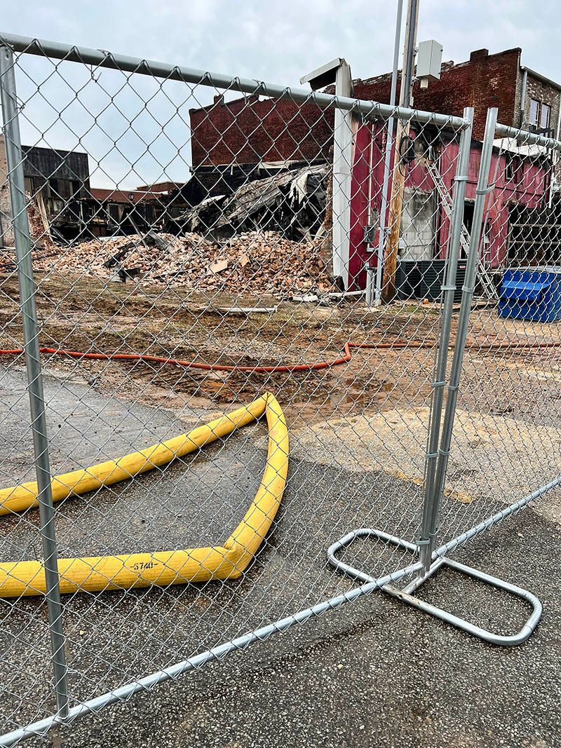 A chain link fence with a yellow hose attached to it.