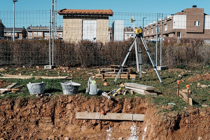 A construction site with a tripod and buckets in the dirt.