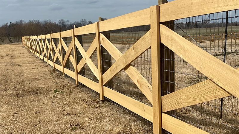 A wooden fence with a fence post in the middle of a field.