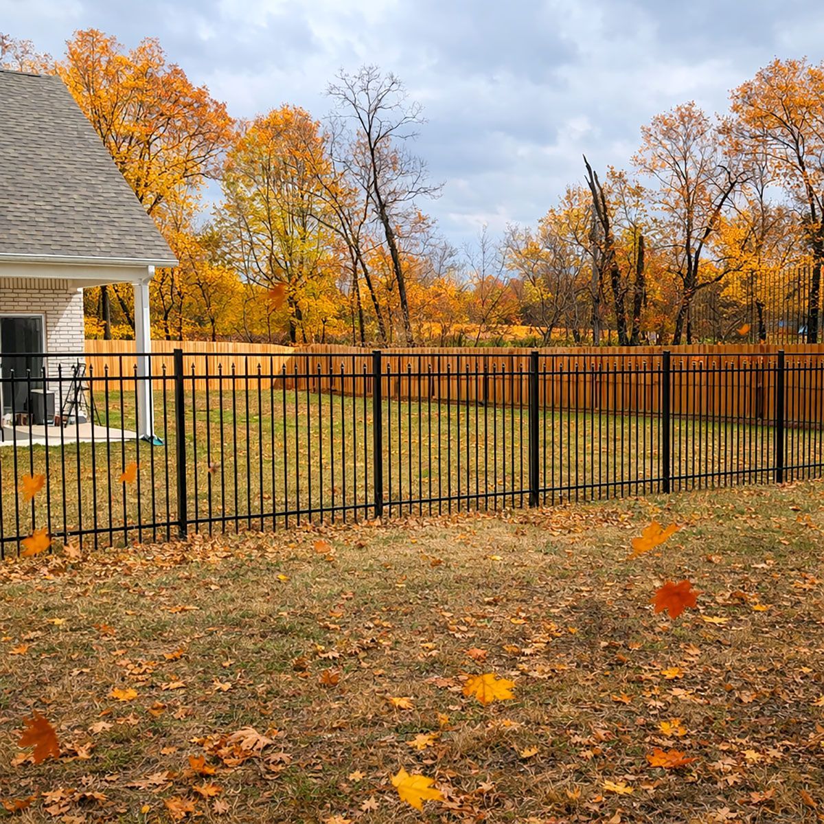 A black metal fence with a gate open on a white background.