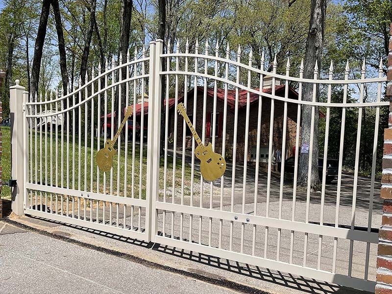 A white metal gate with two guitars on it.