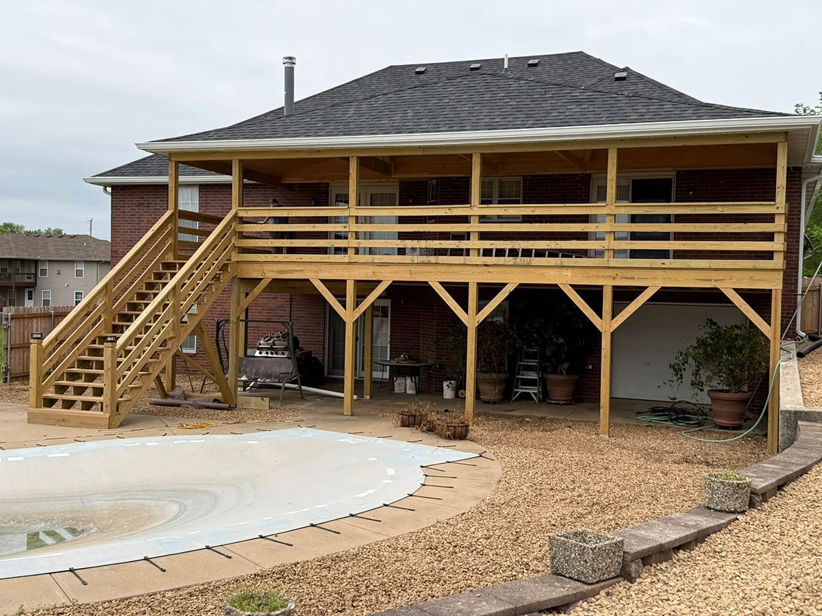 A house with a wooden deck and stairs next to a pool.