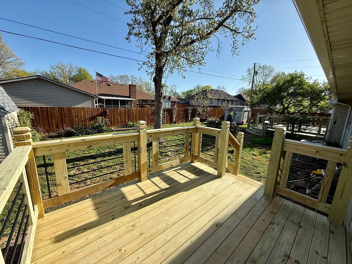A wooden deck with a fence and a gate in the backyard of a house.