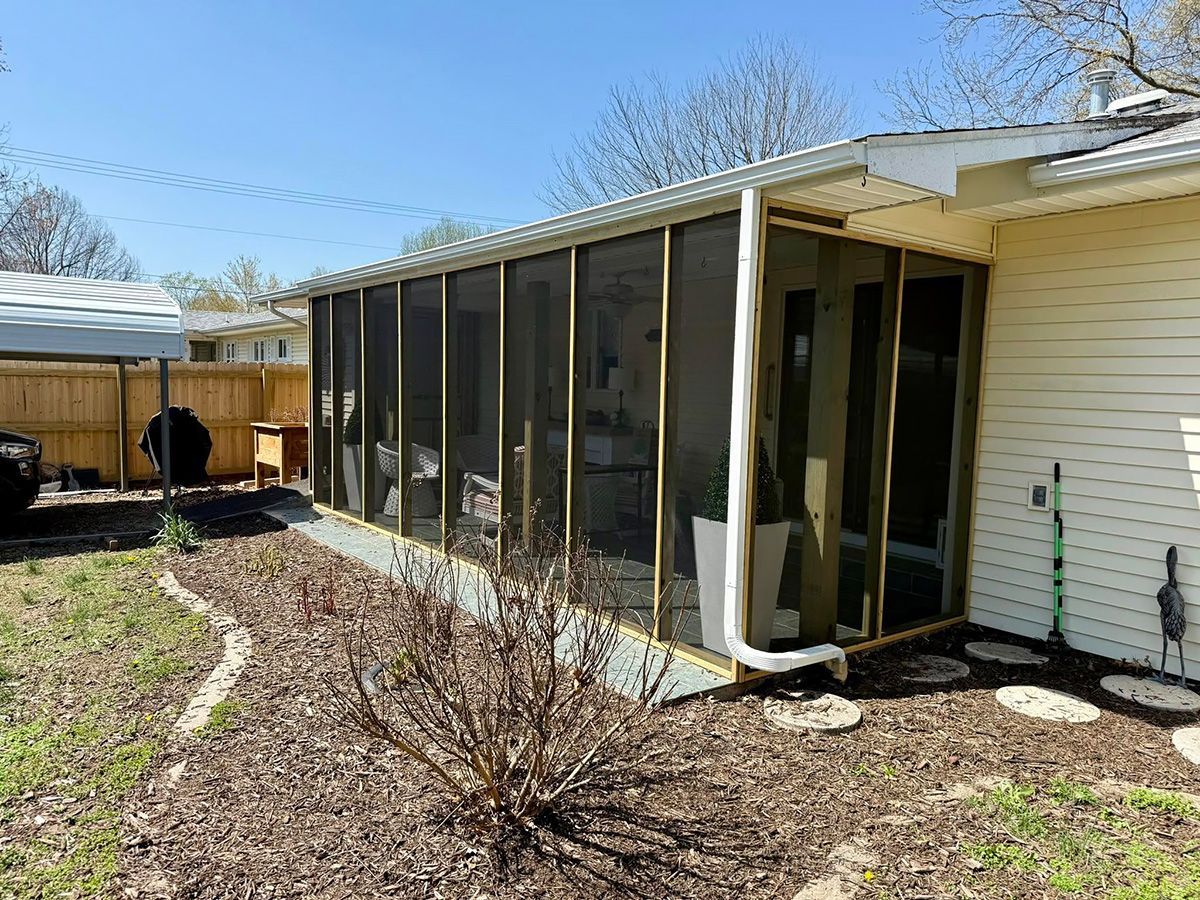 There is a screened in porch in the backyard of a house.