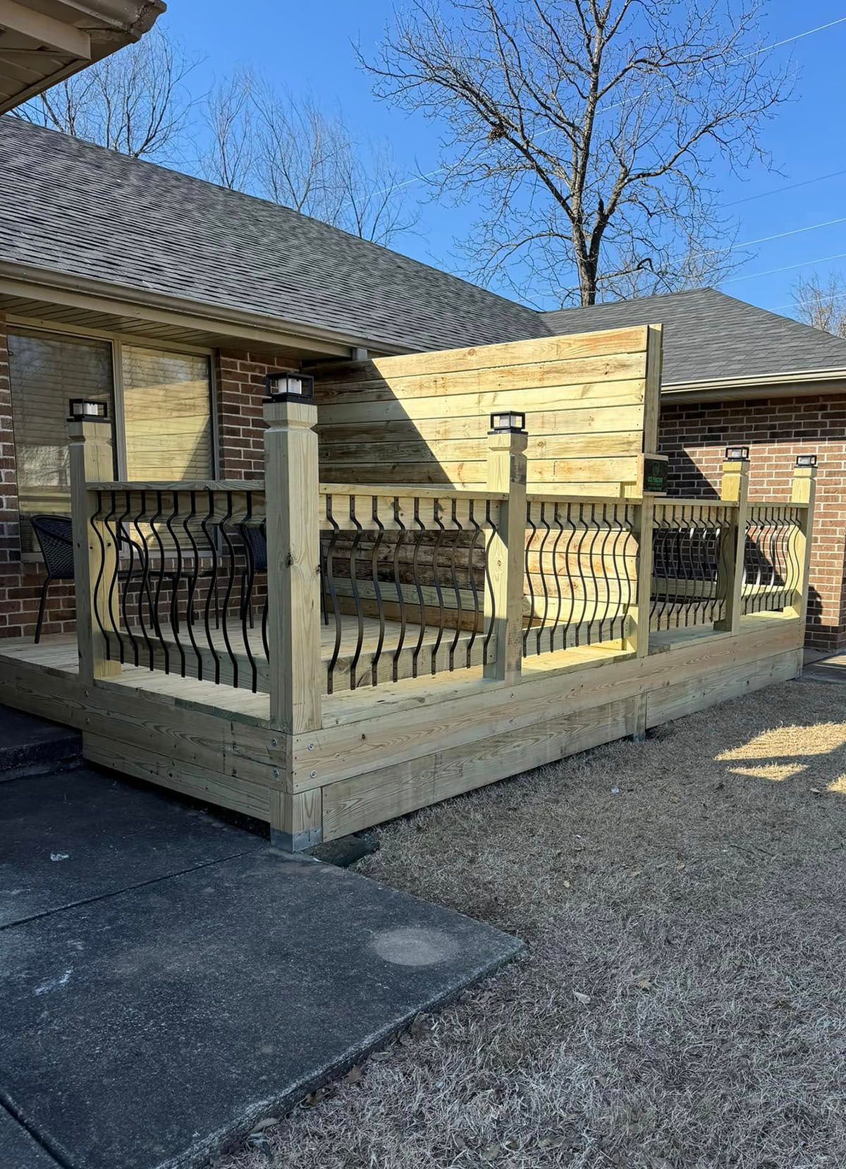 A wooden deck is sitting in front of a brick house.
