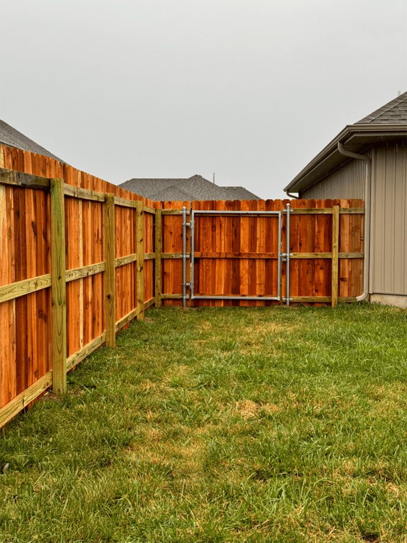A wooden fence with a gate in the backyard of a house.