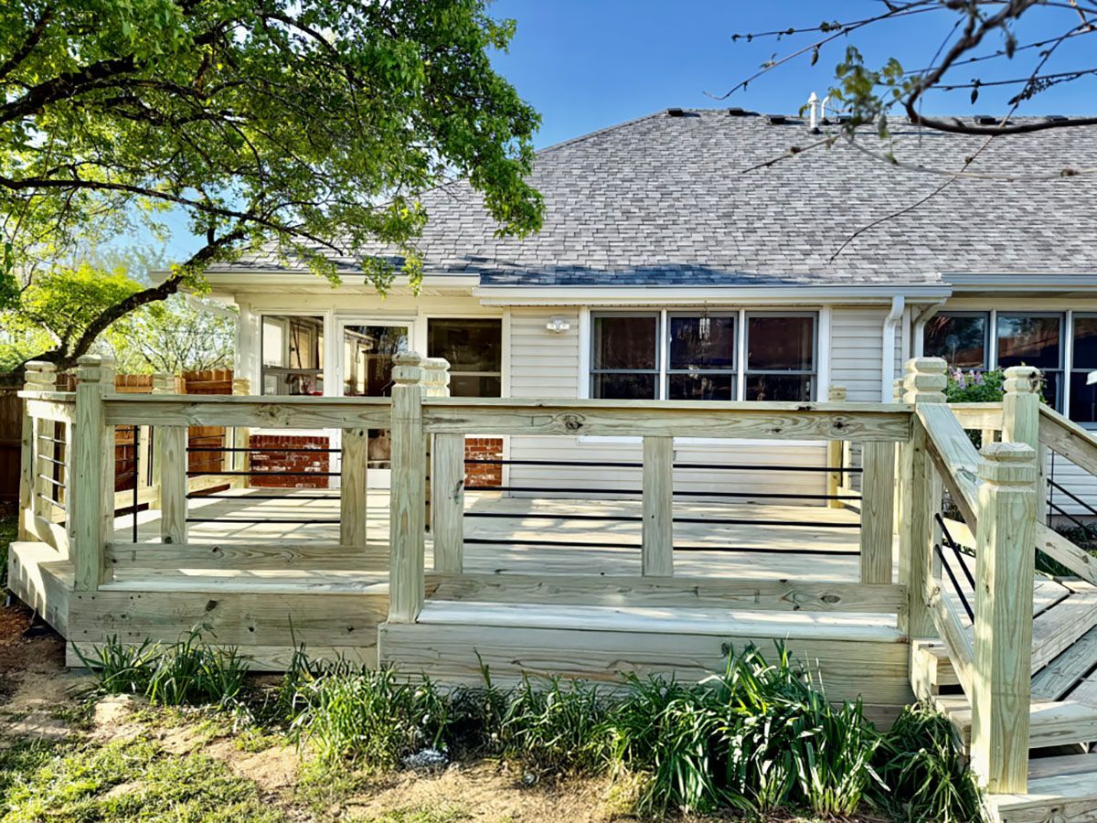 A wooden deck with stairs is in front of a house.