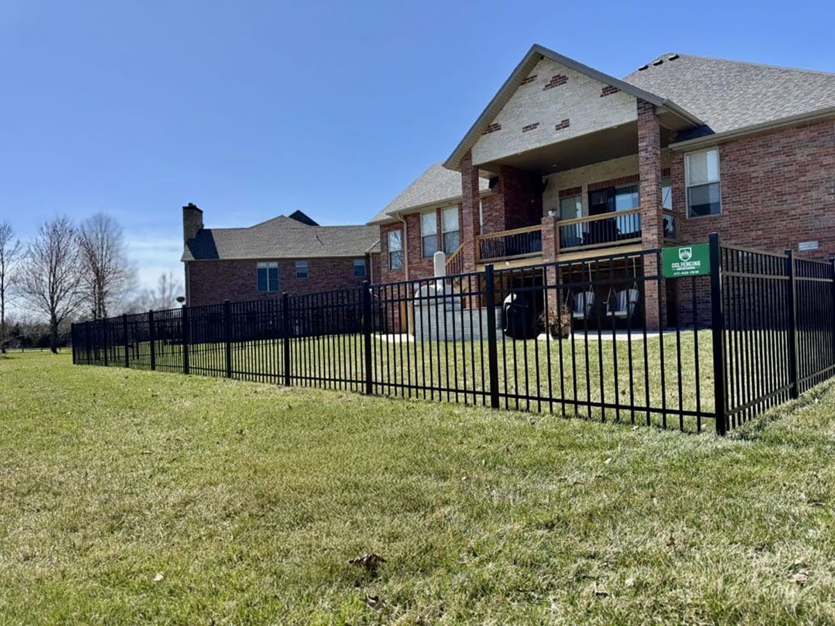 A large brick house with a black fence in front of it.