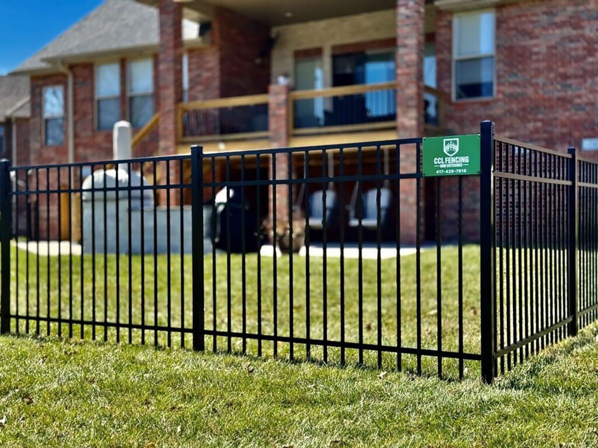 A black metal fence is in front of a brick house.