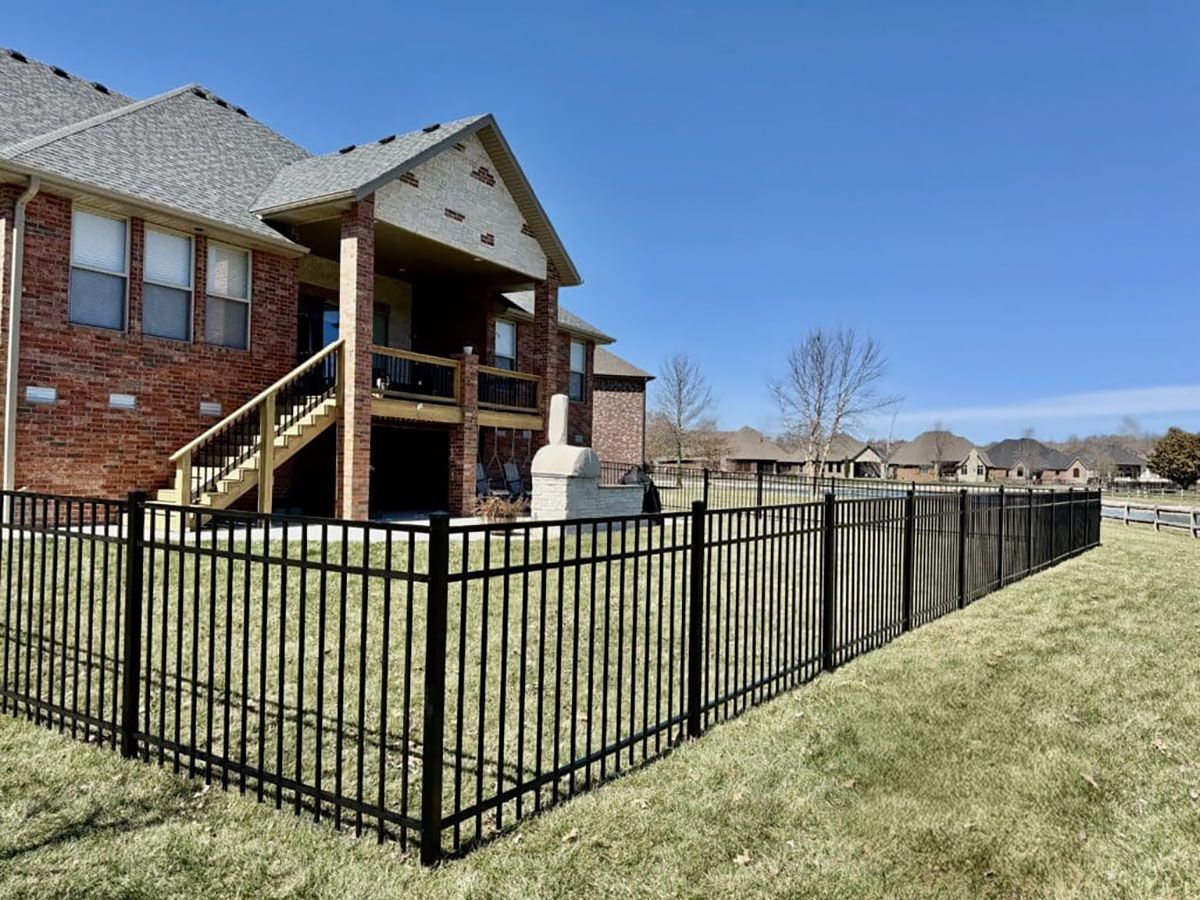 A large brick house with a black fence in front of it.