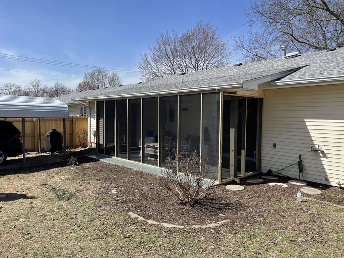 A house with a screened in porch and a carport.
