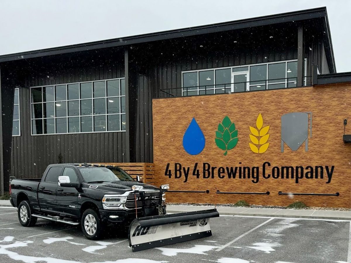 A truck is parked in front of a building that says 4 by 4 brewing company.
