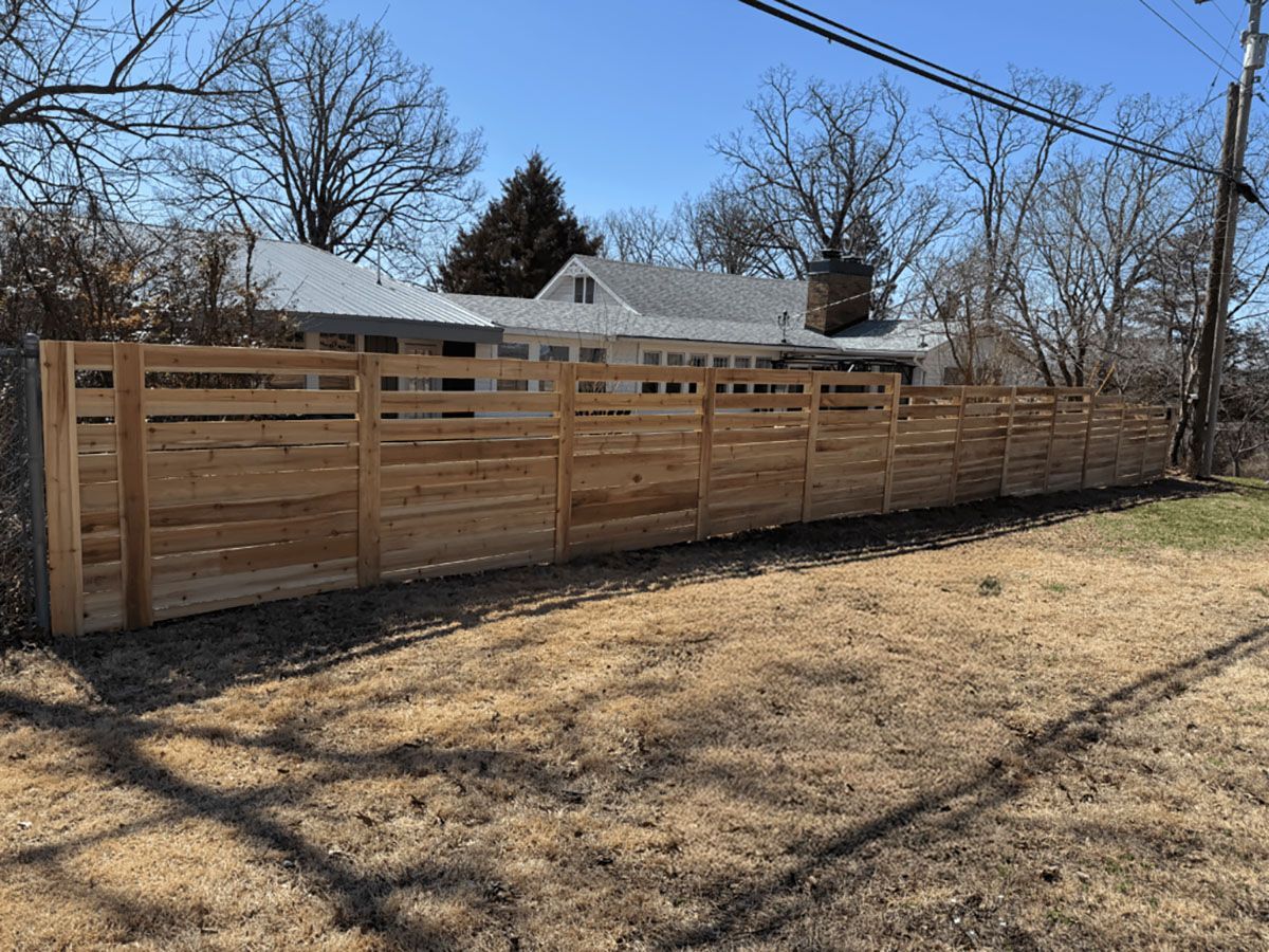 A wooden fence is in the backyard of a house.