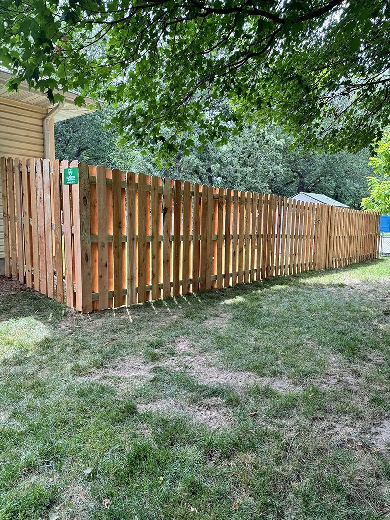 A wooden fence is in the backyard of a house.