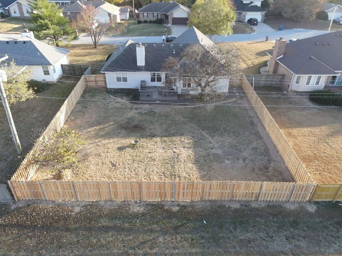An aerial view of a house with a wooden fence around it.
