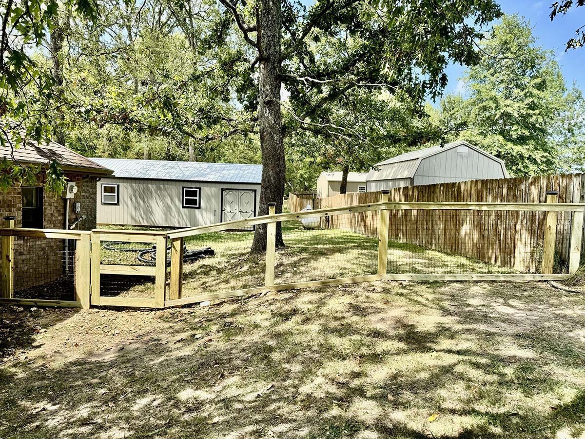 A wooden fence surrounds a yard with a house in the background.