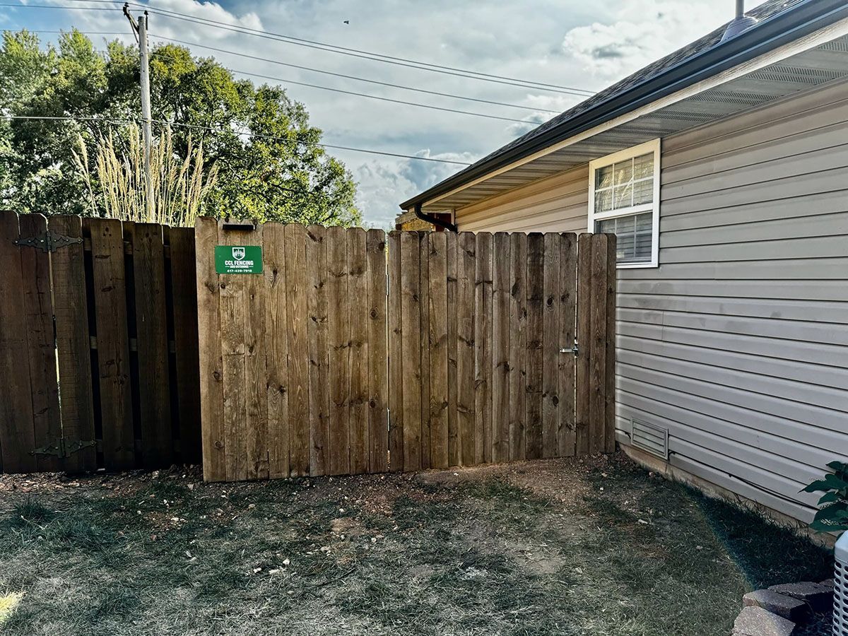 A wooden fence is in the backyard of a house.