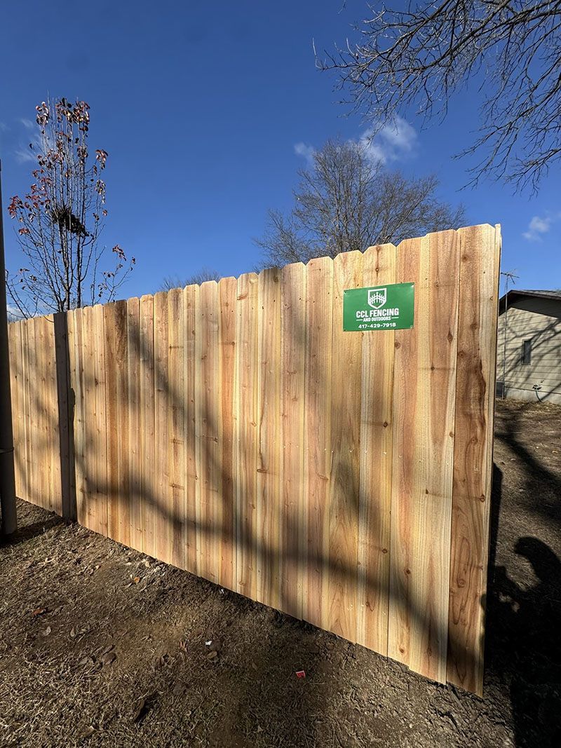 A wooden fence with a green sign on it.