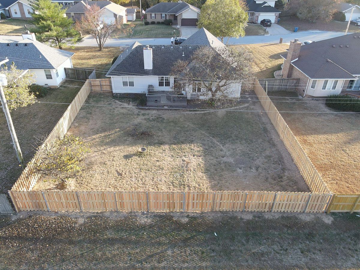 An aerial view of a house and a wooden fence in a residential area.