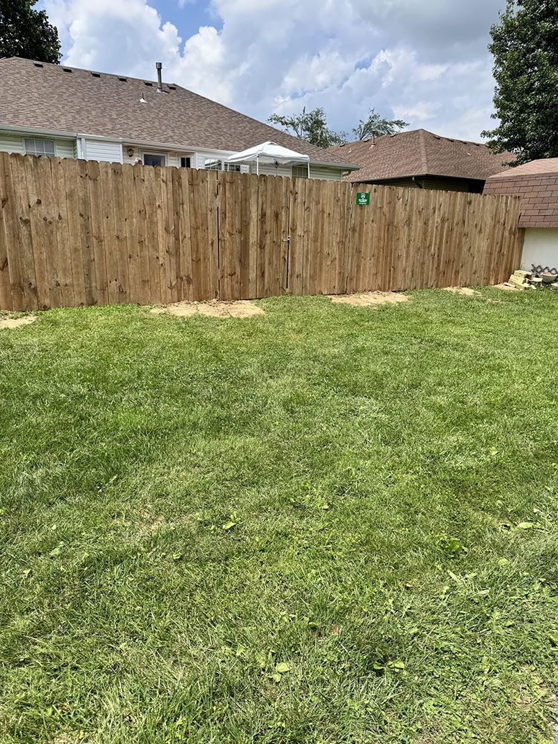 There is a wooden fence in the backyard of a house.