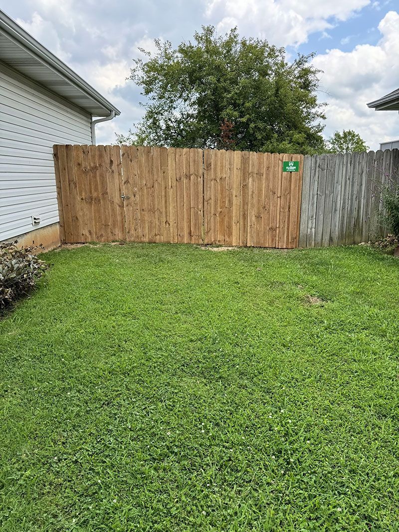 There is a wooden fence in the backyard of a house.