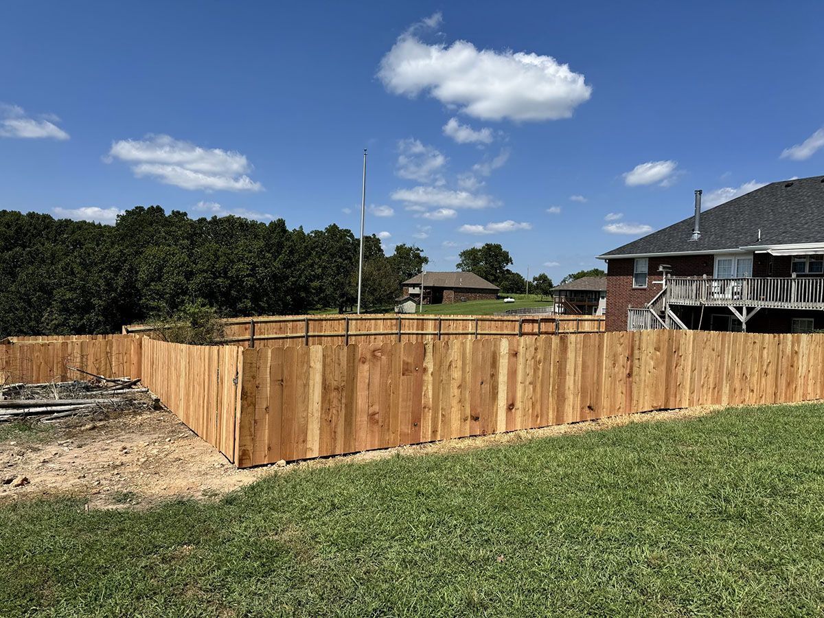 A wooden fence is in the backyard of a house.