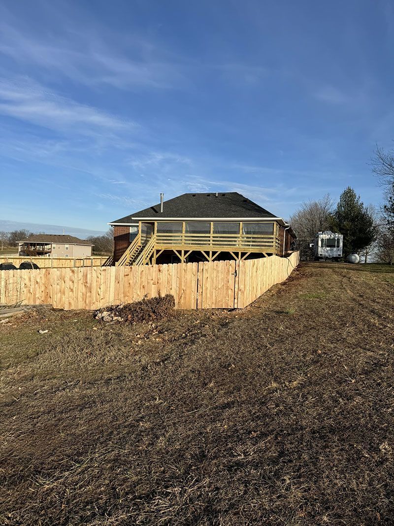 A house with a wooden deck and a wooden fence in front of it.