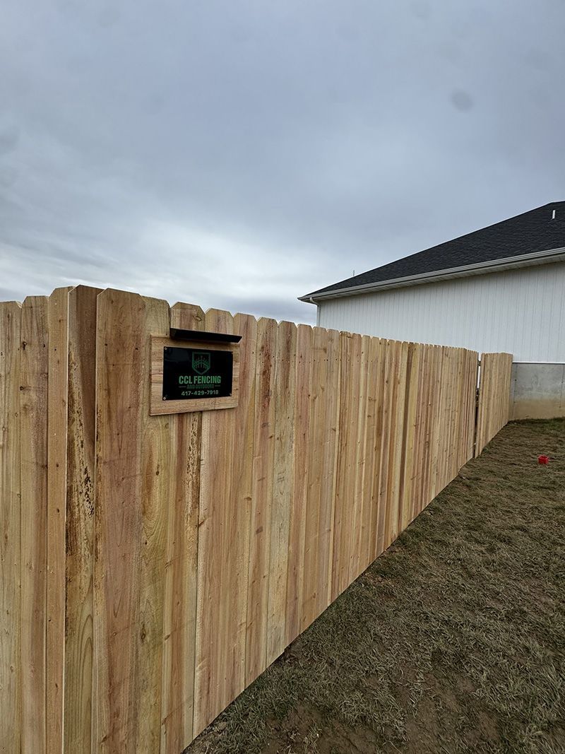 A wooden fence with a mailbox attached to it in front of a house.