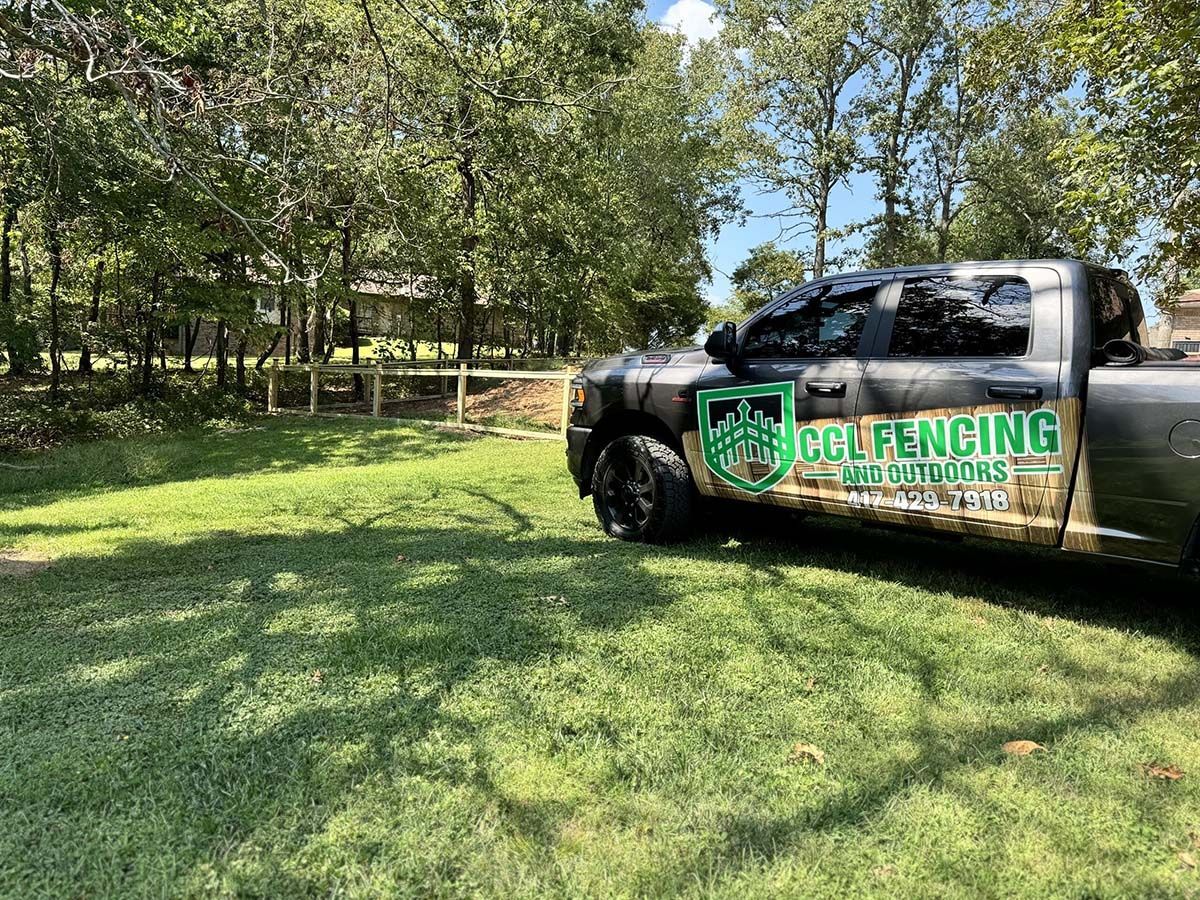 A truck is parked in a grassy field with trees in the background.