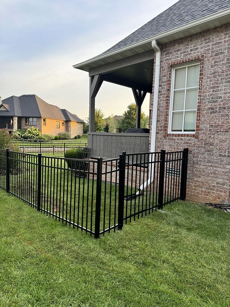 A brick house with a black fence in front of it.