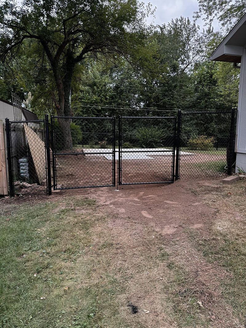 A chain link fence is in the backyard of a house.