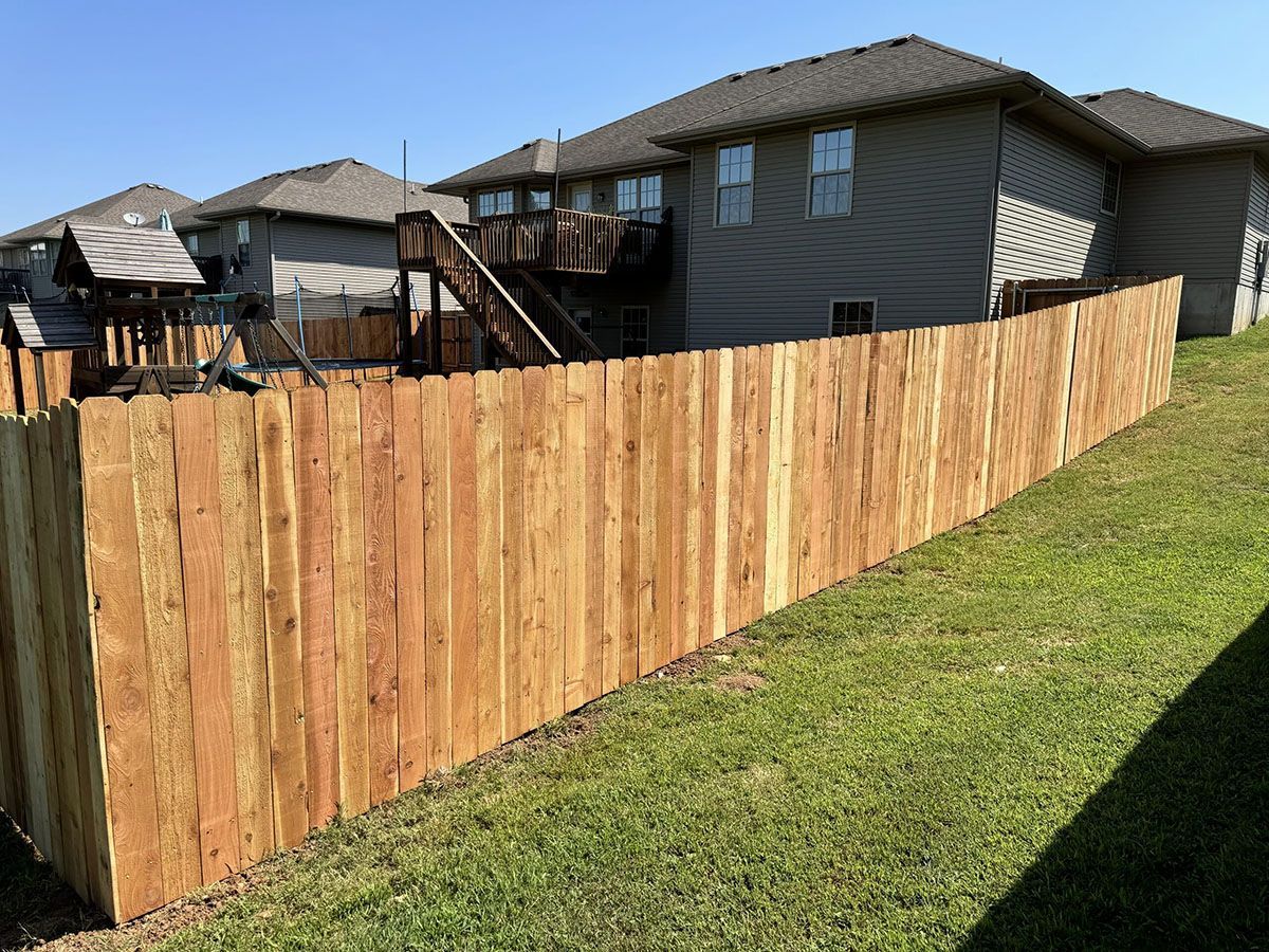 A wooden fence is in the backyard of a house.