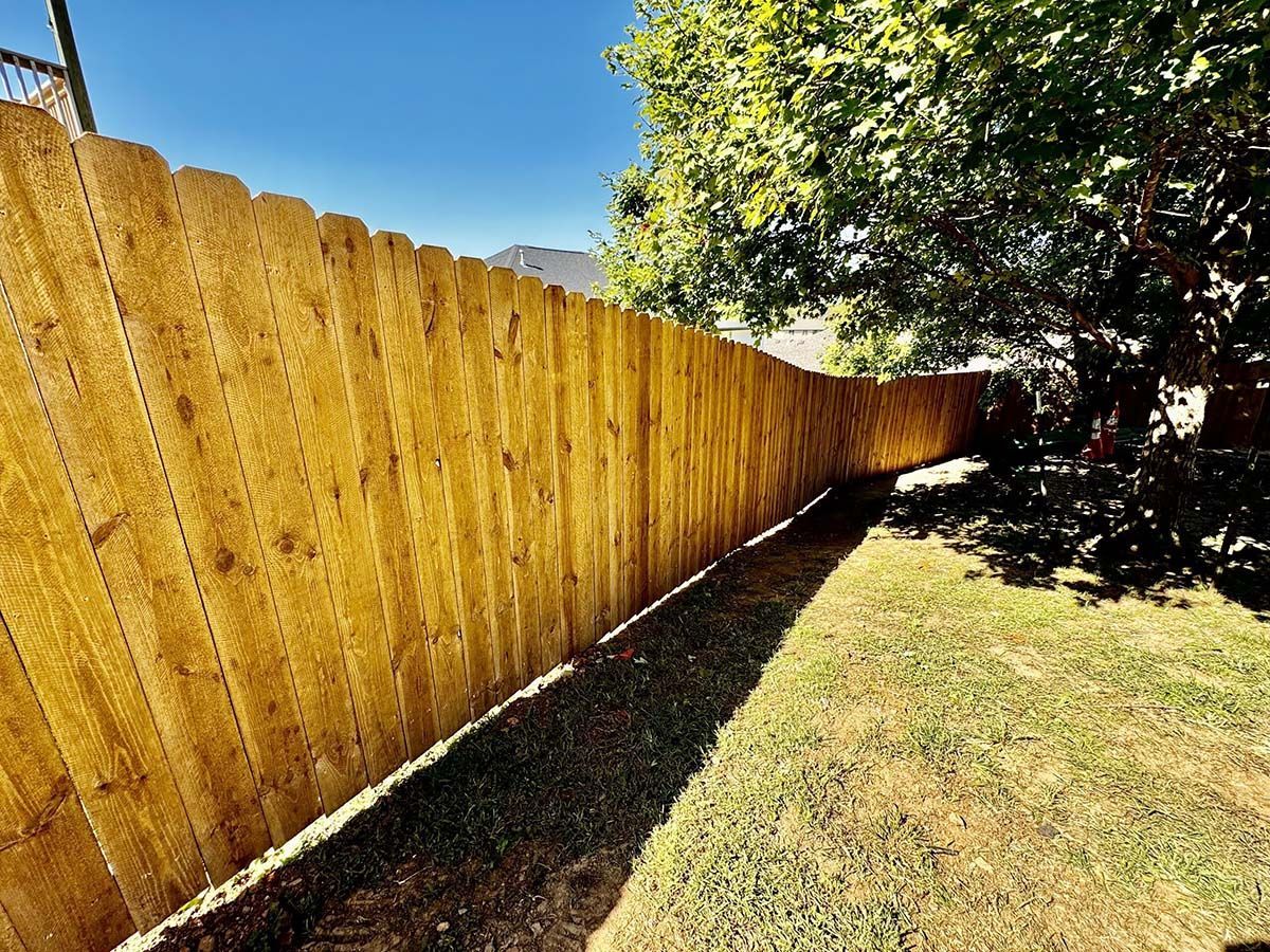 A wooden fence is sitting in the middle of a lush green yard.