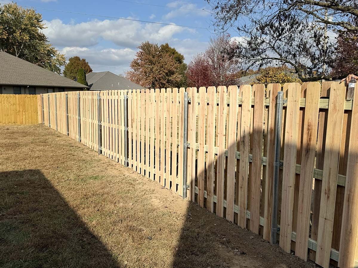 A wooden picket fence is in the backyard of a house.