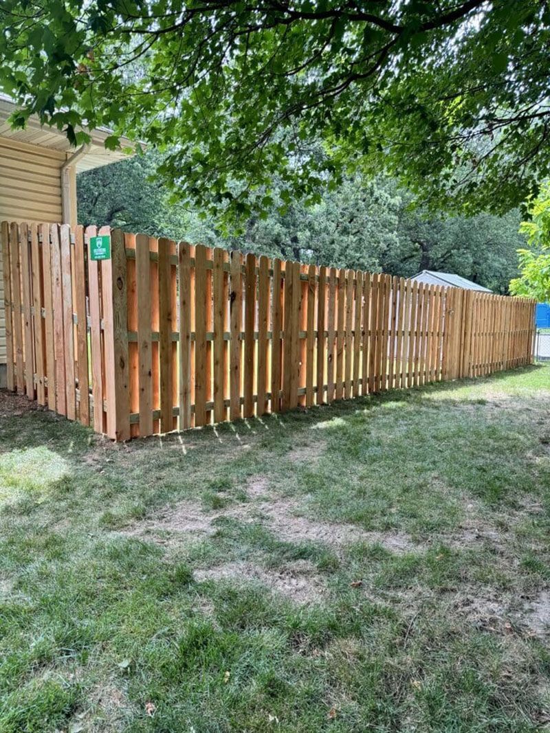 A wooden fence is in the backyard of a house.