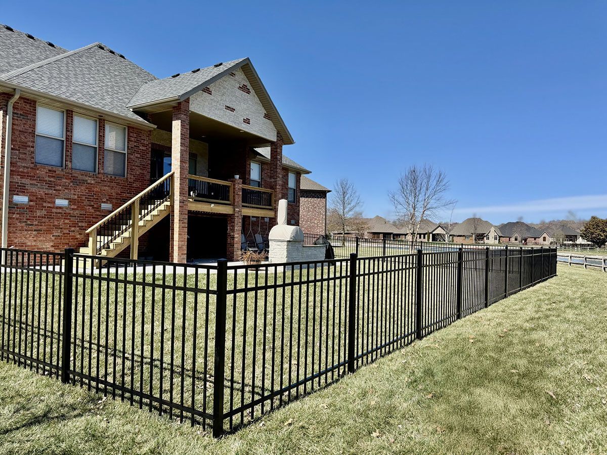 A large brick house with a black fence in front of it.